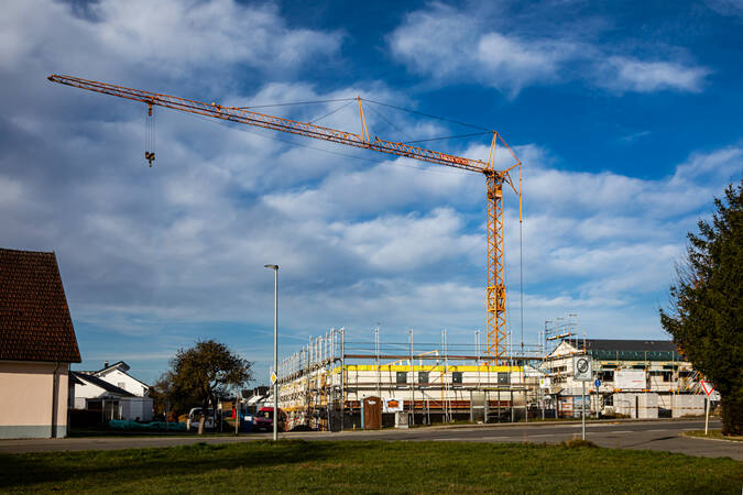 Ein gelber Baukran bei einer Baustelle für ein Haus.