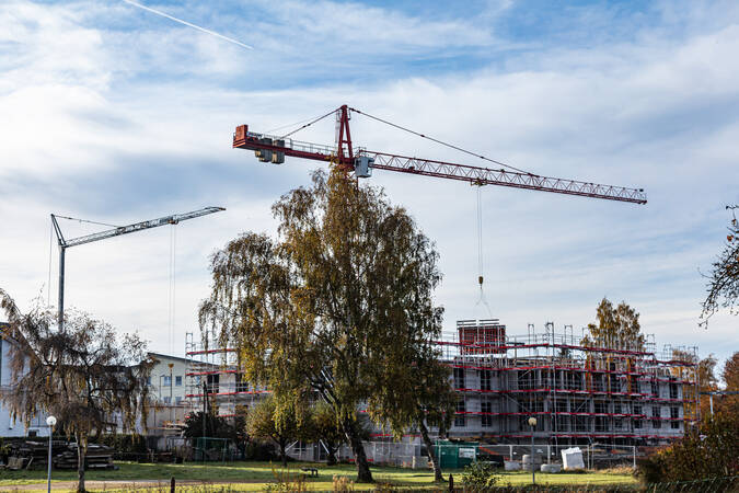 Zwei gelbe Baukräne bei einer Baustelle für ein Haus.
